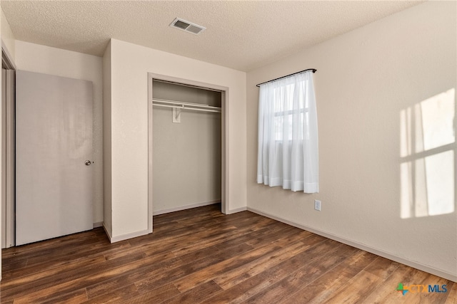 unfurnished bedroom featuring a closet, a textured ceiling, and dark wood-type flooring