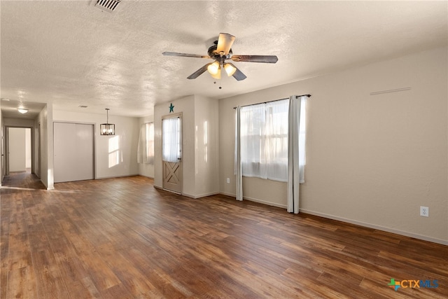 unfurnished room featuring ceiling fan with notable chandelier, dark hardwood / wood-style flooring, and a textured ceiling