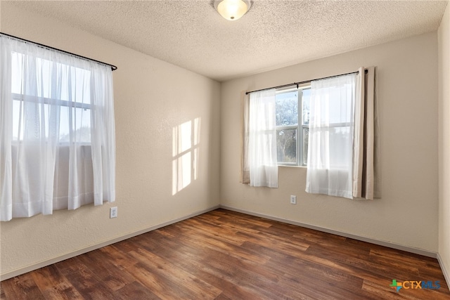 spare room with a textured ceiling and dark hardwood / wood-style flooring