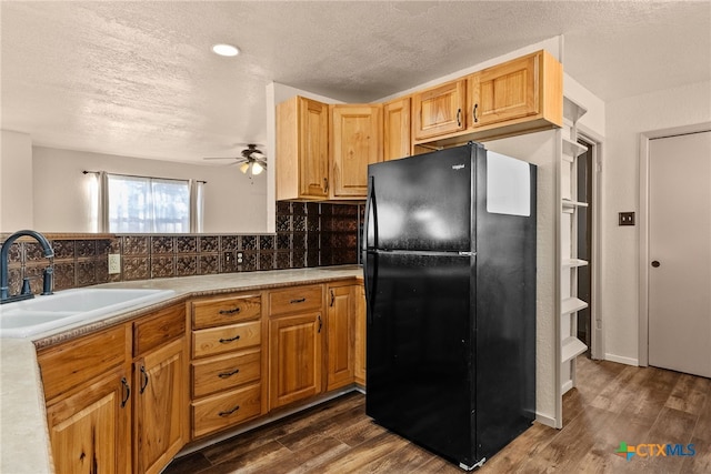 kitchen with sink, black fridge, ceiling fan, tasteful backsplash, and dark hardwood / wood-style flooring