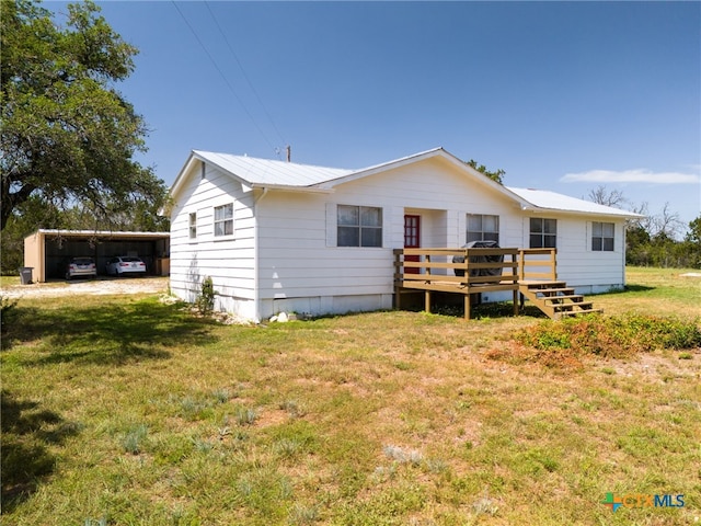 back of property with a lawn, a carport, and a deck