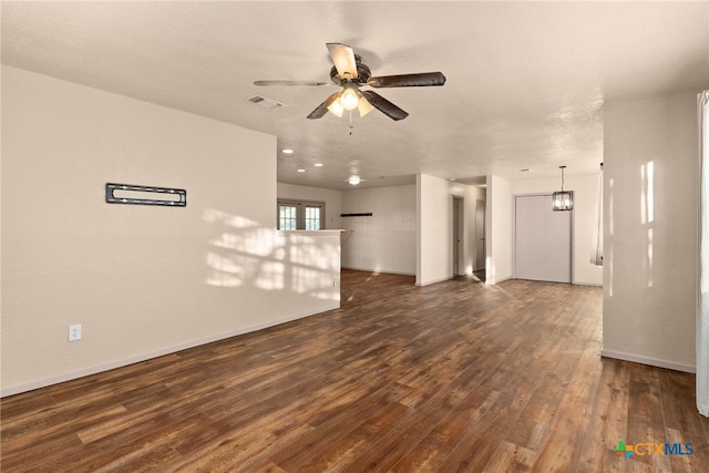 unfurnished living room with a textured ceiling, dark wood-type flooring, and ceiling fan with notable chandelier