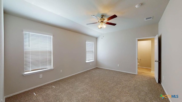 unfurnished bedroom featuring visible vents, ceiling fan, baseboards, carpet floors, and ensuite bath