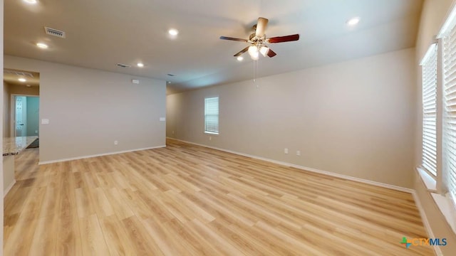 empty room featuring visible vents, light wood-type flooring, and baseboards