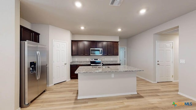 kitchen with visible vents, a kitchen island with sink, a sink, stainless steel appliances, and dark brown cabinetry