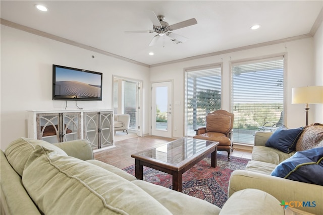 living room with a wealth of natural light, crown molding, ceiling fan, and light tile patterned flooring