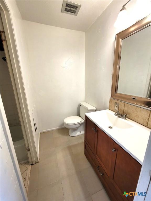 bathroom with toilet, vanity, visible vents, tasteful backsplash, and a bathtub