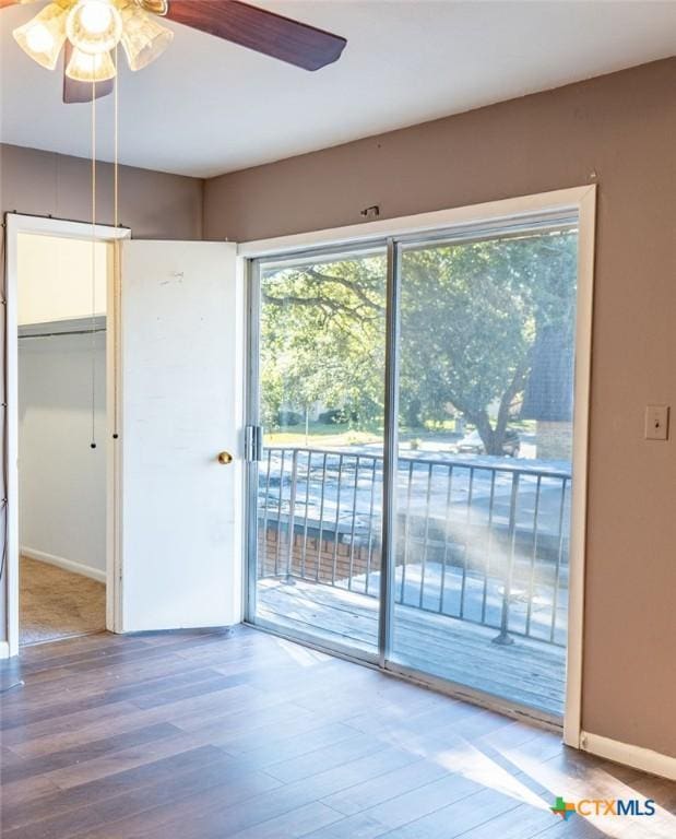 interior space with a ceiling fan, baseboards, and wood finished floors