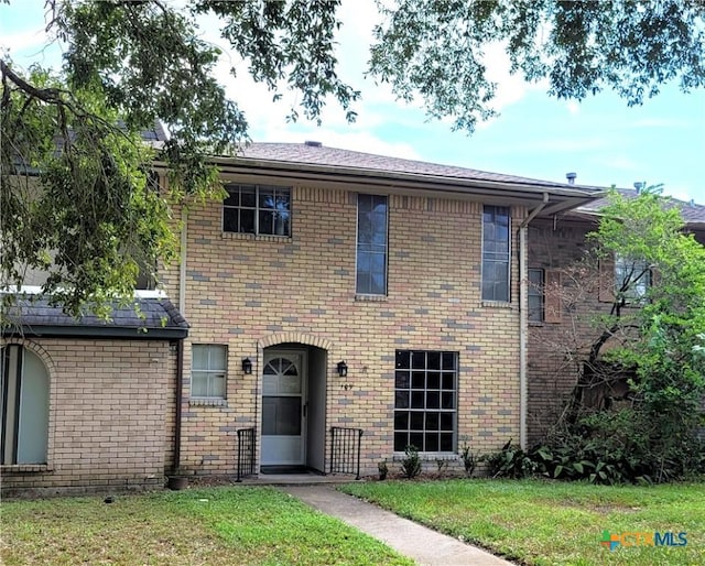 view of front of house featuring a front yard and brick siding