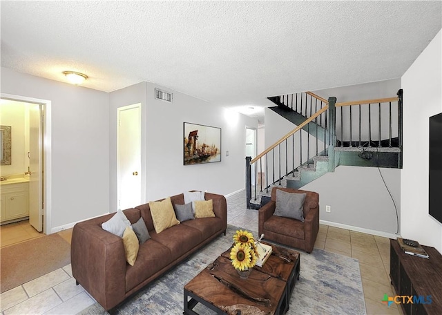 living area featuring light tile patterned floors, baseboards, visible vents, stairs, and a textured ceiling