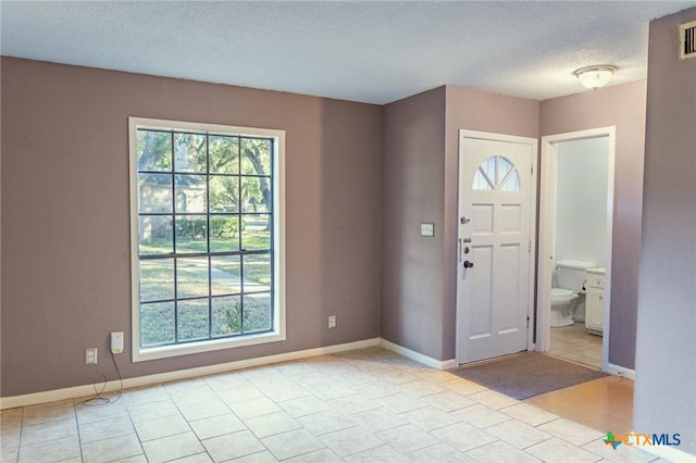 entrance foyer featuring a textured ceiling, baseboards, and a wealth of natural light