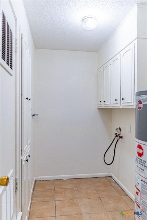 clothes washing area featuring a textured ceiling, washer hookup, visible vents, baseboards, and water heater