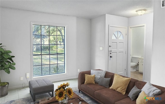 living room with a textured ceiling, visible vents, a wealth of natural light, and light tile patterned flooring