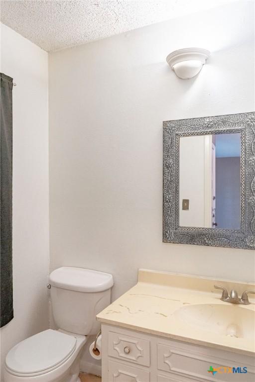 bathroom with toilet, a textured ceiling, and vanity