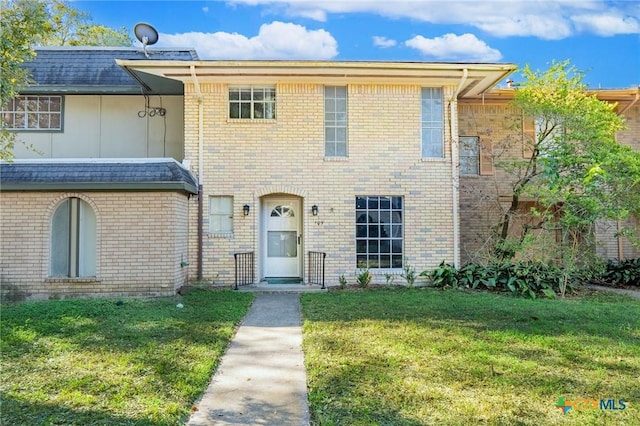 view of front of house with a front yard and brick siding