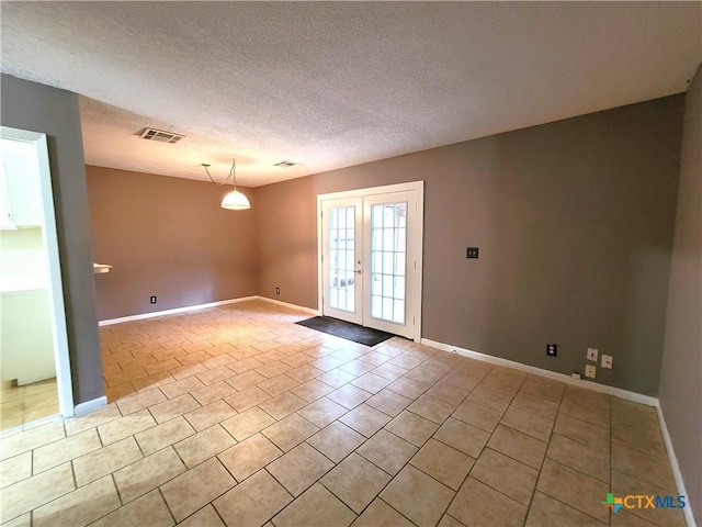 empty room with light tile patterned floors, visible vents, a textured ceiling, and french doors