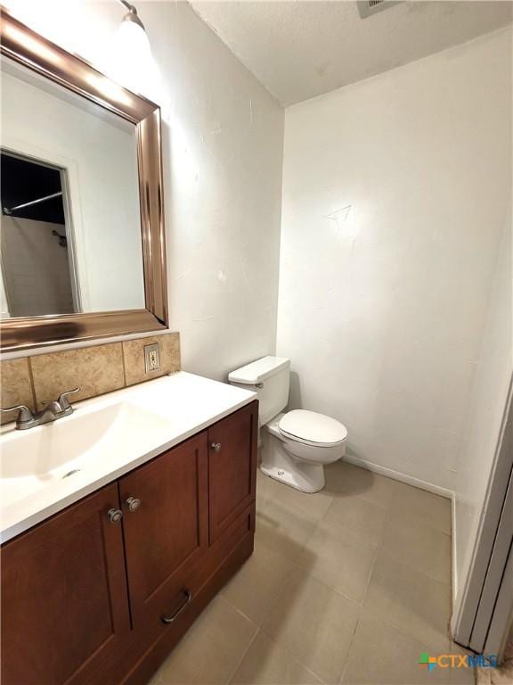 bathroom featuring toilet, decorative backsplash, and vanity