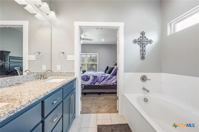 bathroom featuring ceiling fan, plenty of natural light, a tub, and vanity