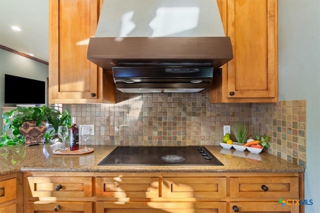 kitchen with black electric stovetop, backsplash, light stone counters, and exhaust hood