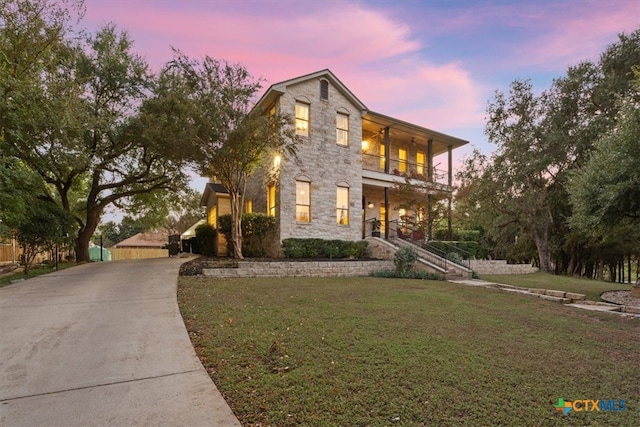 view of front of house with a balcony and a lawn