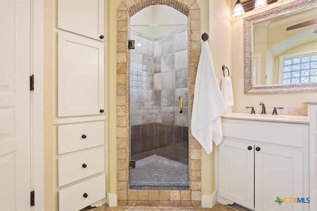 bathroom featuring a tiled fireplace, a shower with door, and vanity