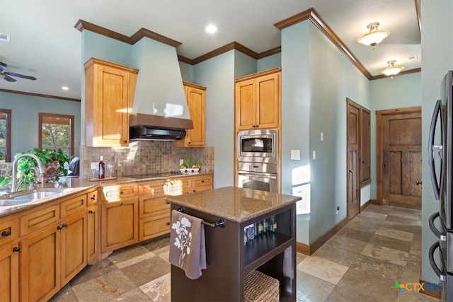 kitchen with wall chimney range hood, stainless steel appliances, ornamental molding, and sink