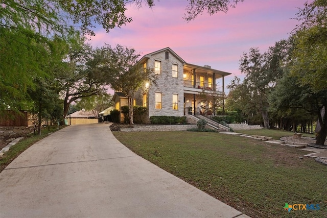 view of front of house with a lawn and a balcony