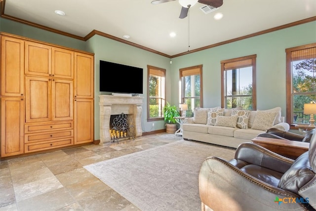 living room with ceiling fan, a fireplace, a healthy amount of sunlight, and ornamental molding