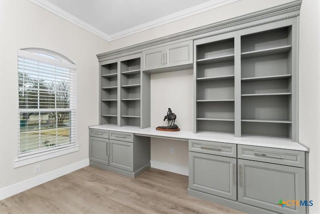 unfurnished office featuring light hardwood / wood-style flooring, crown molding, and built in desk