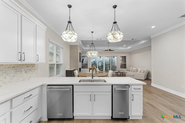 kitchen with a tray ceiling, pendant lighting, sink, white cabinets, and kitchen peninsula