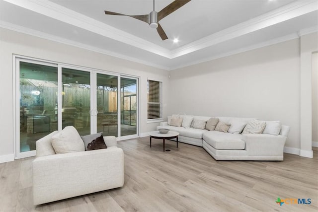 living room with a ceiling fan, crown molding, baseboards, and wood finished floors