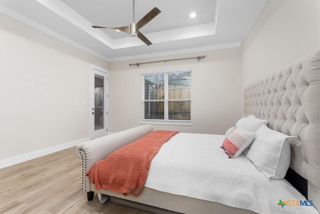 bedroom with a tray ceiling, ornamental molding, ceiling fan, and hardwood / wood-style flooring