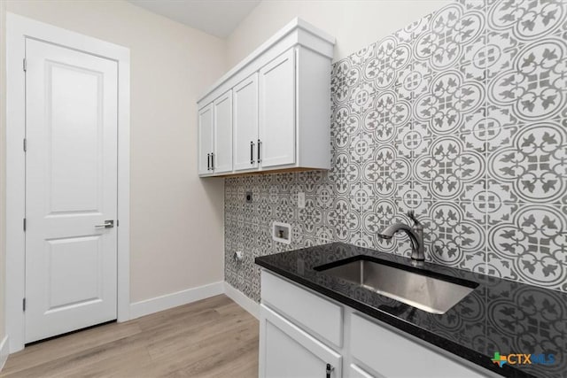 interior space featuring sink, white cabinetry, tasteful backsplash, light hardwood / wood-style flooring, and dark stone counters