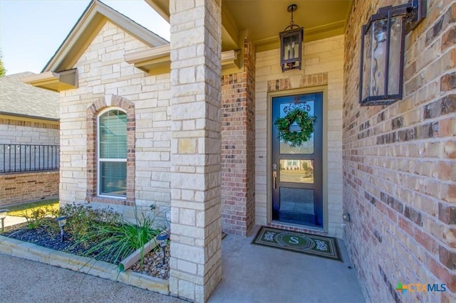 doorway to property featuring brick siding and a shingled roof