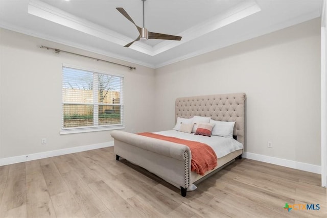 bedroom featuring a tray ceiling, baseboards, wood finished floors, and crown molding