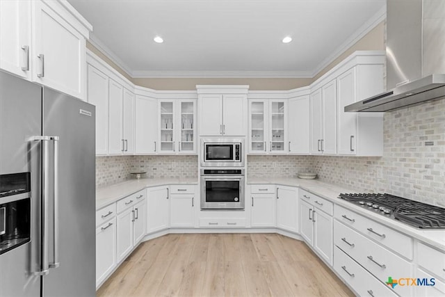 kitchen with stainless steel appliances, white cabinets, and wall chimney exhaust hood