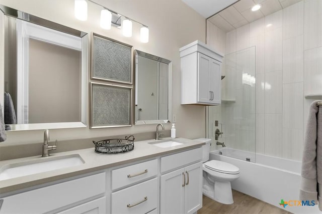 bathroom with double vanity, toilet, wood finished floors, and a sink