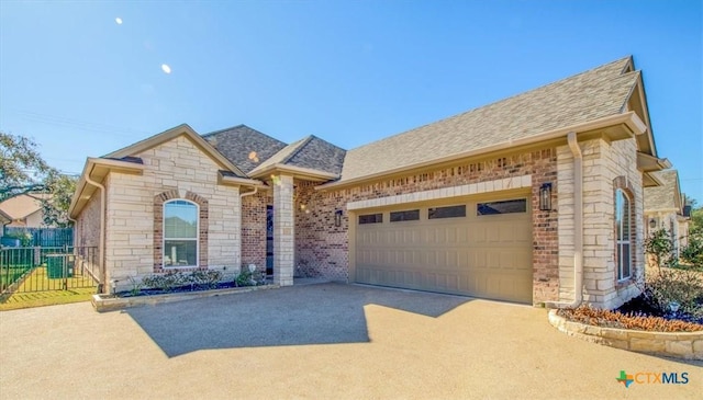 view of front of home featuring a garage, a shingled roof, concrete driveway, and fence