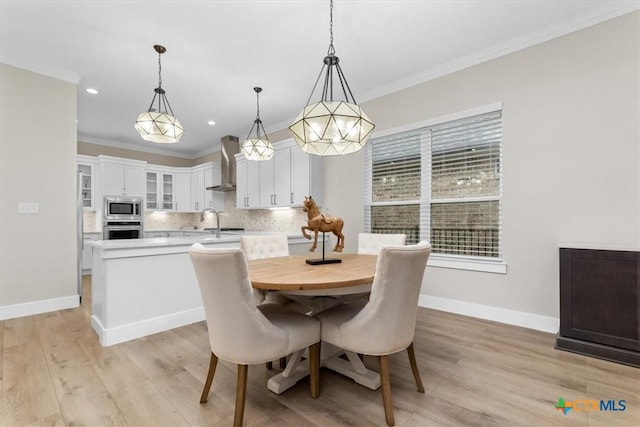 dining room featuring light wood-type flooring, baseboards, and crown molding