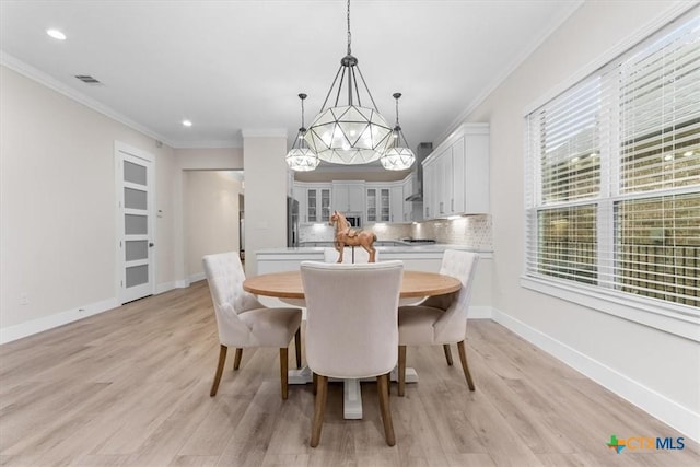 dining space with an inviting chandelier, ornamental molding, and light hardwood / wood-style floors