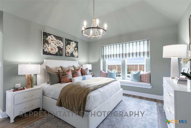 bedroom with baseboards, vaulted ceiling, an inviting chandelier, and wood finished floors