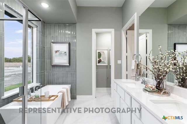 full bathroom with a freestanding tub, a sink, baseboards, marble finish floor, and double vanity