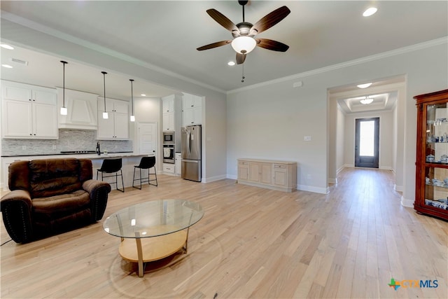 living room featuring ceiling fan, light hardwood / wood-style floors, and crown molding