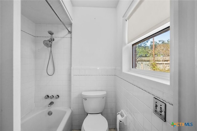 bathroom featuring toilet, tile walls, and tiled shower / bath