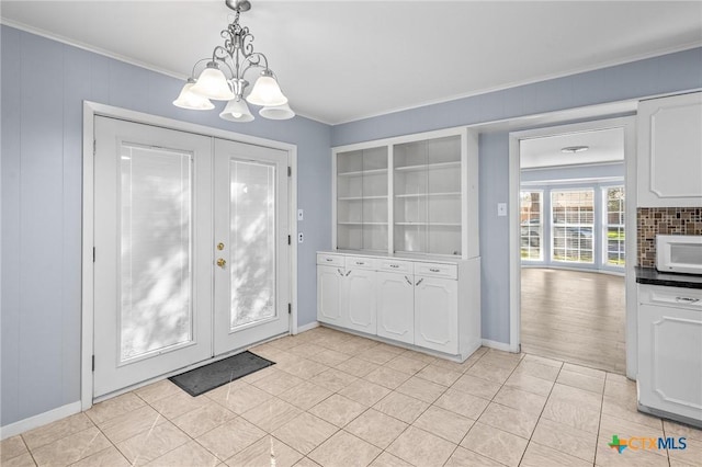 doorway featuring an inviting chandelier and crown molding