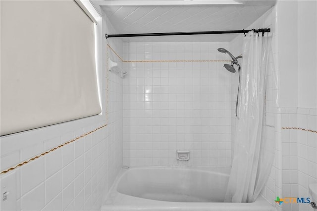 bathroom with shower / tub combo and tile walls