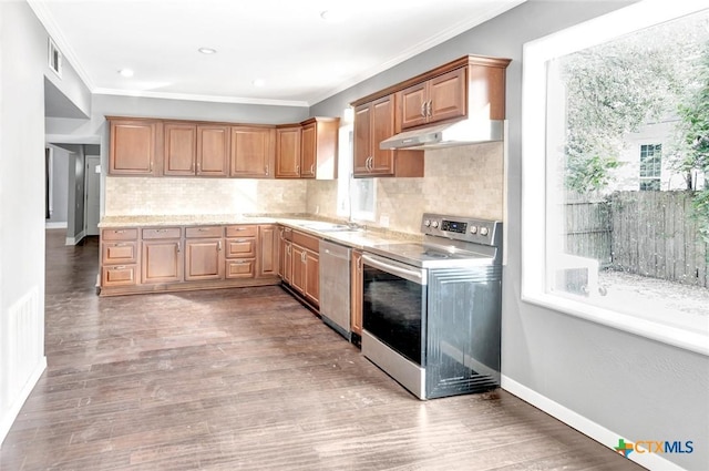 214 Hubbard St, Yoakum, TX 77995 - kitchen featuring stainless steel appliances, under cabinet range hood, crown molding, decorative backsplash, and baseboards