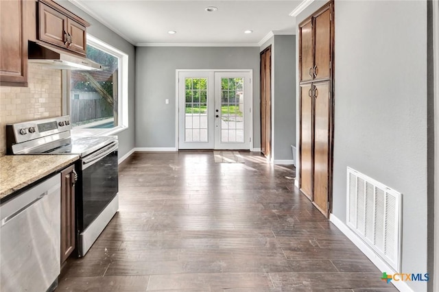 214 Hubbard St, Yoakum, TX 77995 - kitchen featuring appliances with stainless steel finishes, under cabinet range hood, ornamental molding, backsplash, and baseboards