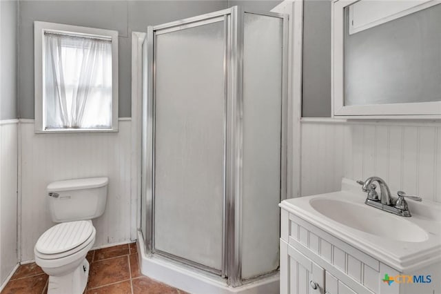 214 Hubbard St, Yoakum, TX 77995 - bathroom featuring a stall shower, toilet, vanity, a wainscoted wall, and tile patterned flooring