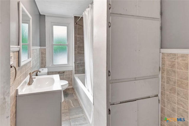 214 Hubbard St, Yoakum, TX 77995 - full bathroom with tile walls, vanity, shower / bath combo, a wainscoted wall, and toilet
